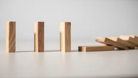 Three wood blocks standing upright as others fall